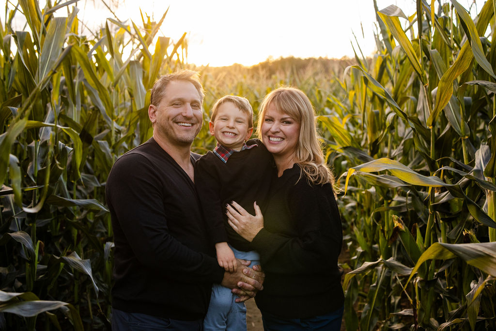 Family poses inside the corn field at The Farmer's Daughter in Kingstown, RI for their fall portrait session