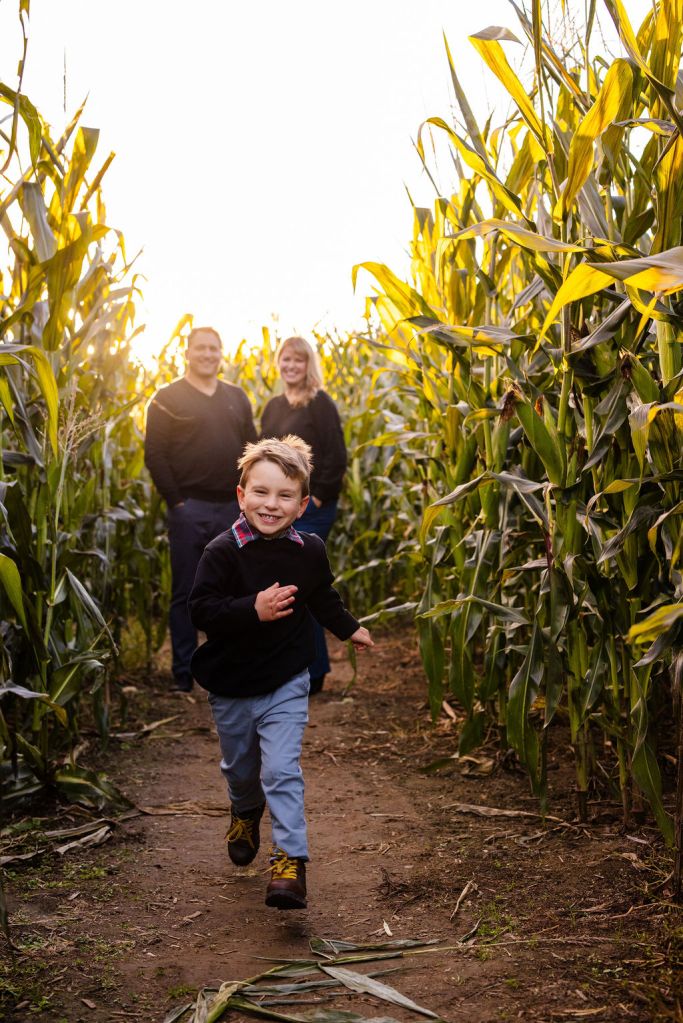 Family poses inside the corn field at The Farmer's Daughter in Kingstown, RI for their fall portrait session